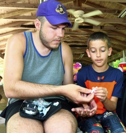 A camp counselor shares snacks with a child